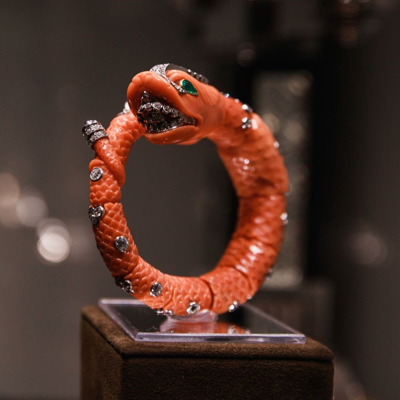 CARVED CORAL, EMERALD, AND DIAMOND CHIMERA BANGLE BY CARTIER, PARIS, CIRCA 1960